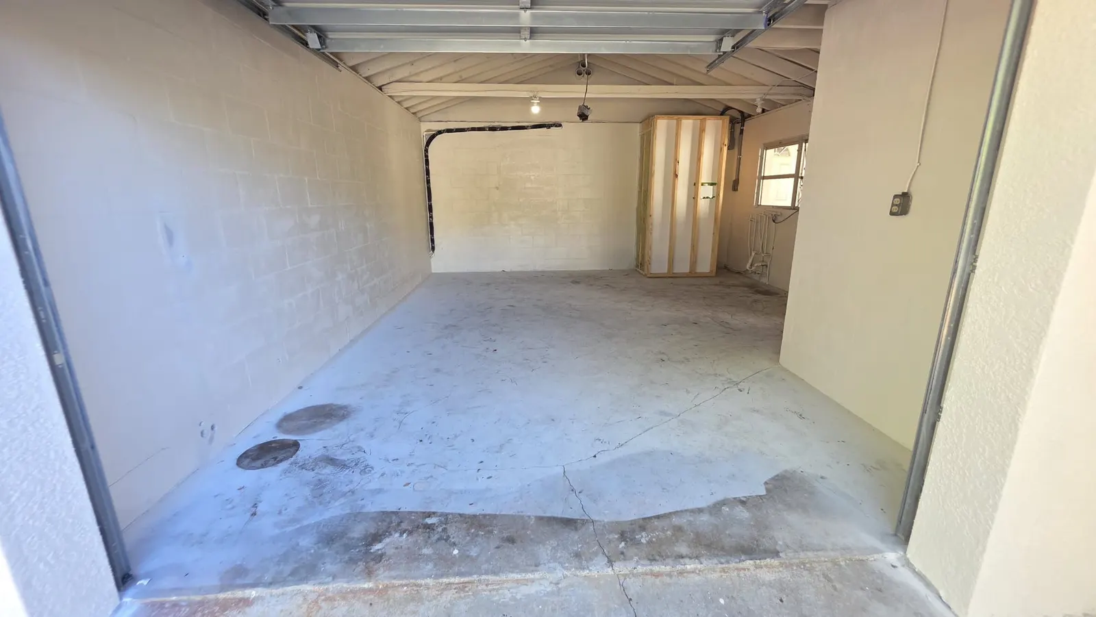 Garage floor before epoxy: bare concrete with oil stains and a long crack