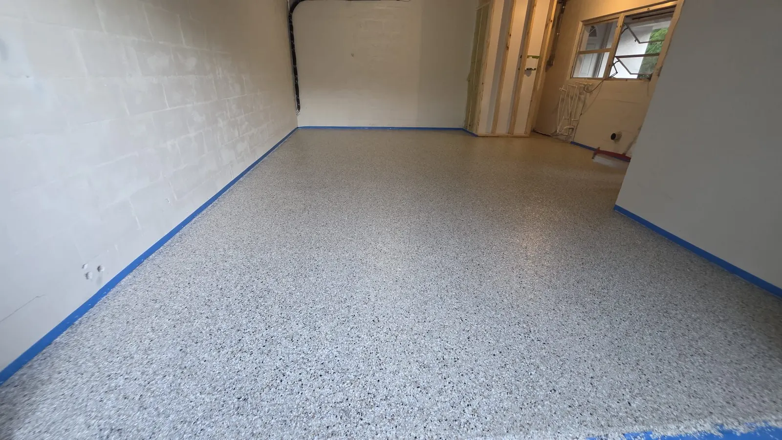 Flake epoxy garage floor with the walls masked in blue tape during installation