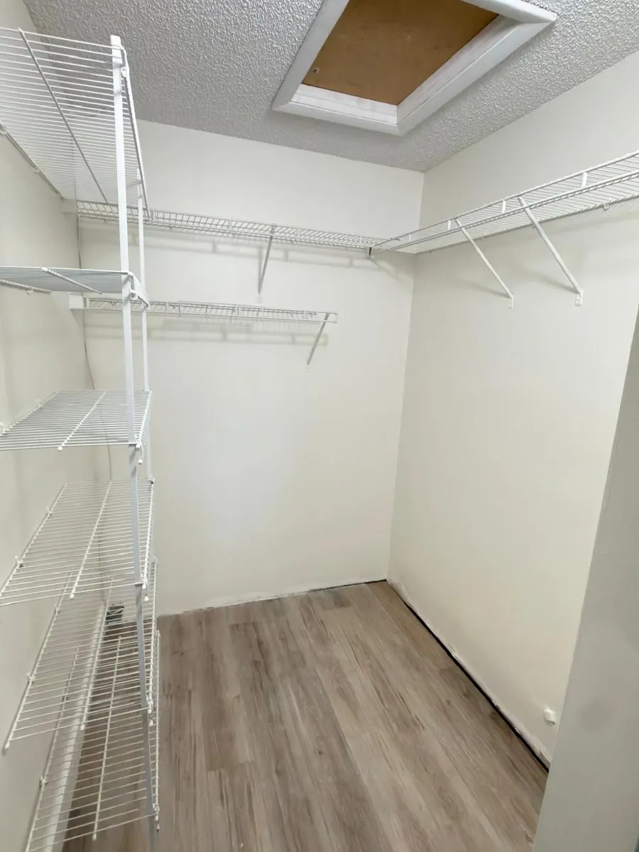 Clóset vestidor con paredes recién pintadas y repisas blancas de alambre