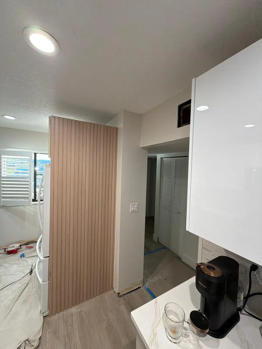 Cocina y pasillo con paredes recién pintadas en blanco hueso y el piso todavía cubierto durante el trabajo